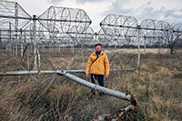 Astronomer Mikhail Sidorchuk in front of UTR-2 radio telescope antennas damaged by Russian soldier shooting.